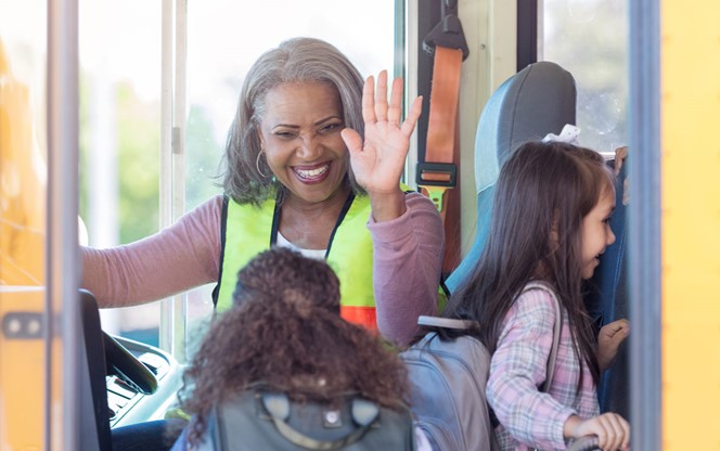 Female Bus Driver High Fives Children Boarding Bus