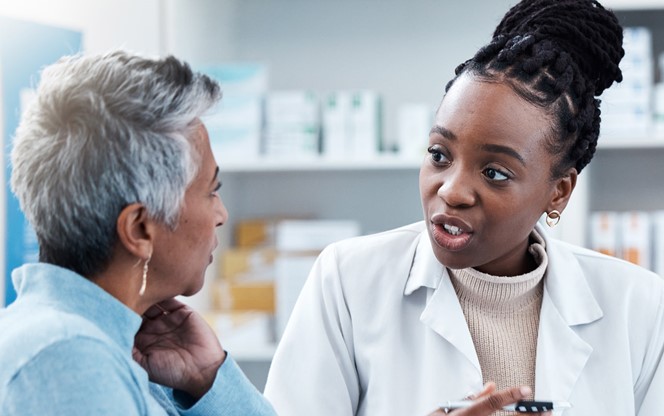 Pharmacist reviewing health plan cost trends with customer Female Medicine Professional Helping A Patient In A Drugstore