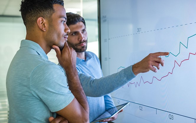 Two Male Colleagues Looking At Data On Screen