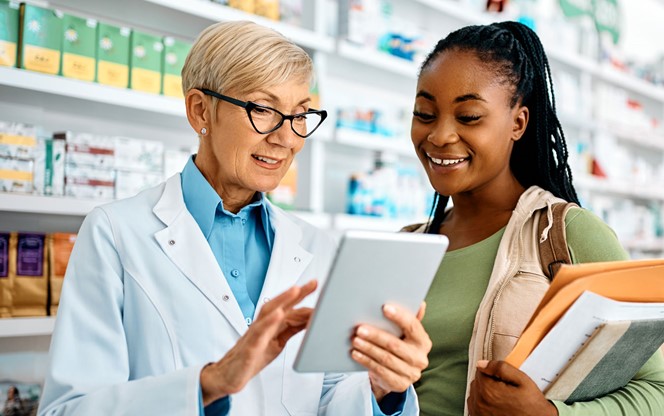Senior Pharmacist And Young Black Woman Using Touchpad In A Pharmacy