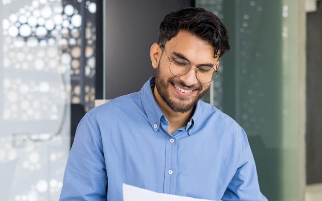 Young Indian Man On A Laptop Working With Documents At The Office